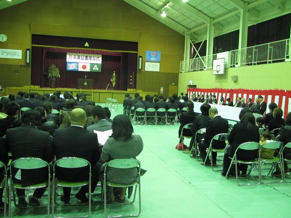 卒業式に出席した卒業生と保護者、右側に来賓客が椅子に座っている写真